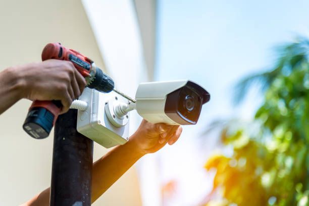 Technicien IROMBI-ELECTRONET installant une caméra de surveillance